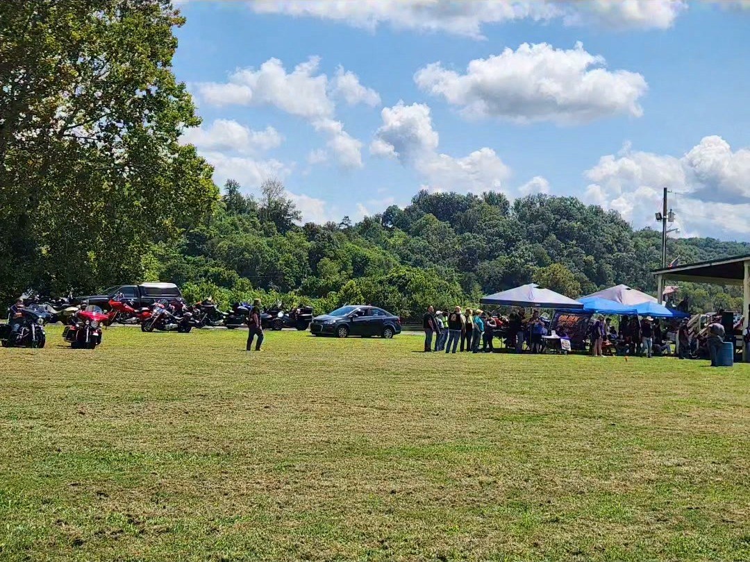 A crowd gathered under tents at an outdoor community event.