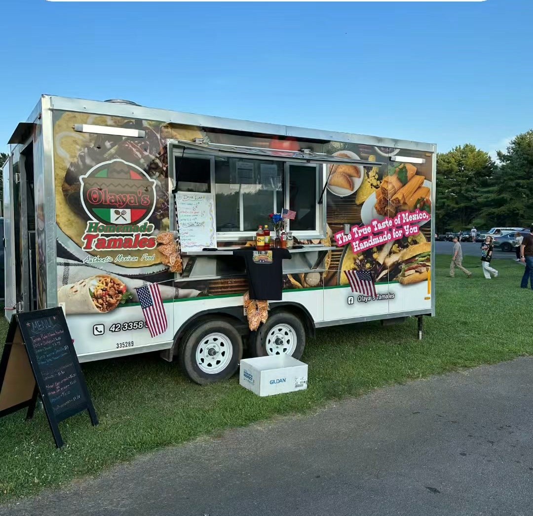 The Olaya's Tamales food truck set up on the grass with its serving window open on a clear day.